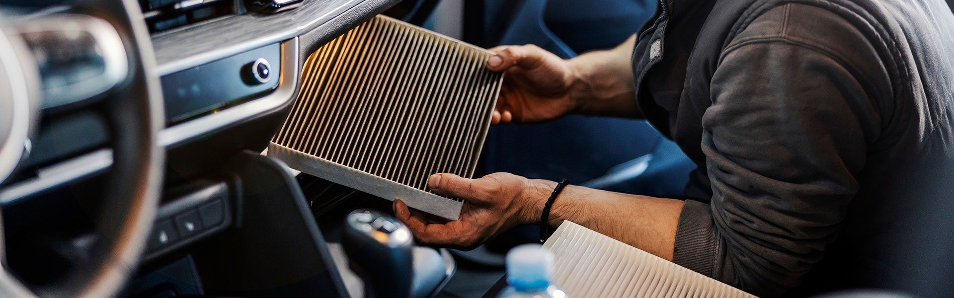 Professional technician replacing a cabin air filter inside a vehicle.