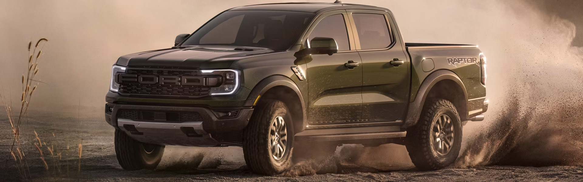 green Ford Ranger Raptor pickup truck kicking up dust.