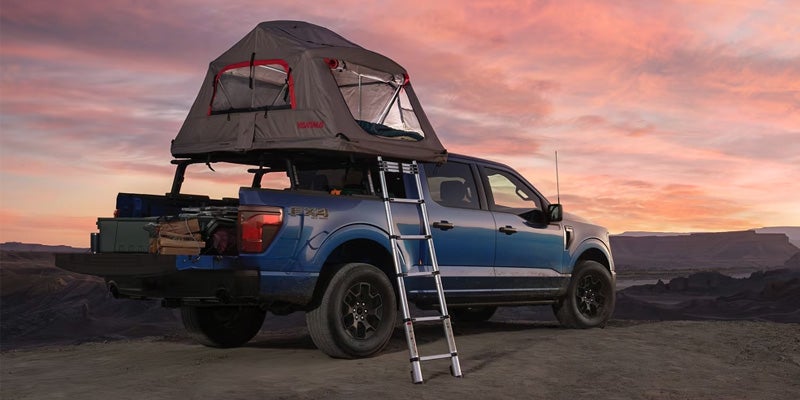 Ford F-150 with rooftop tent setup at sunset in desert.